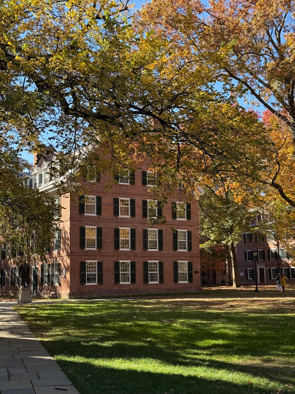 A historic brick building framed by autumn foliage.
