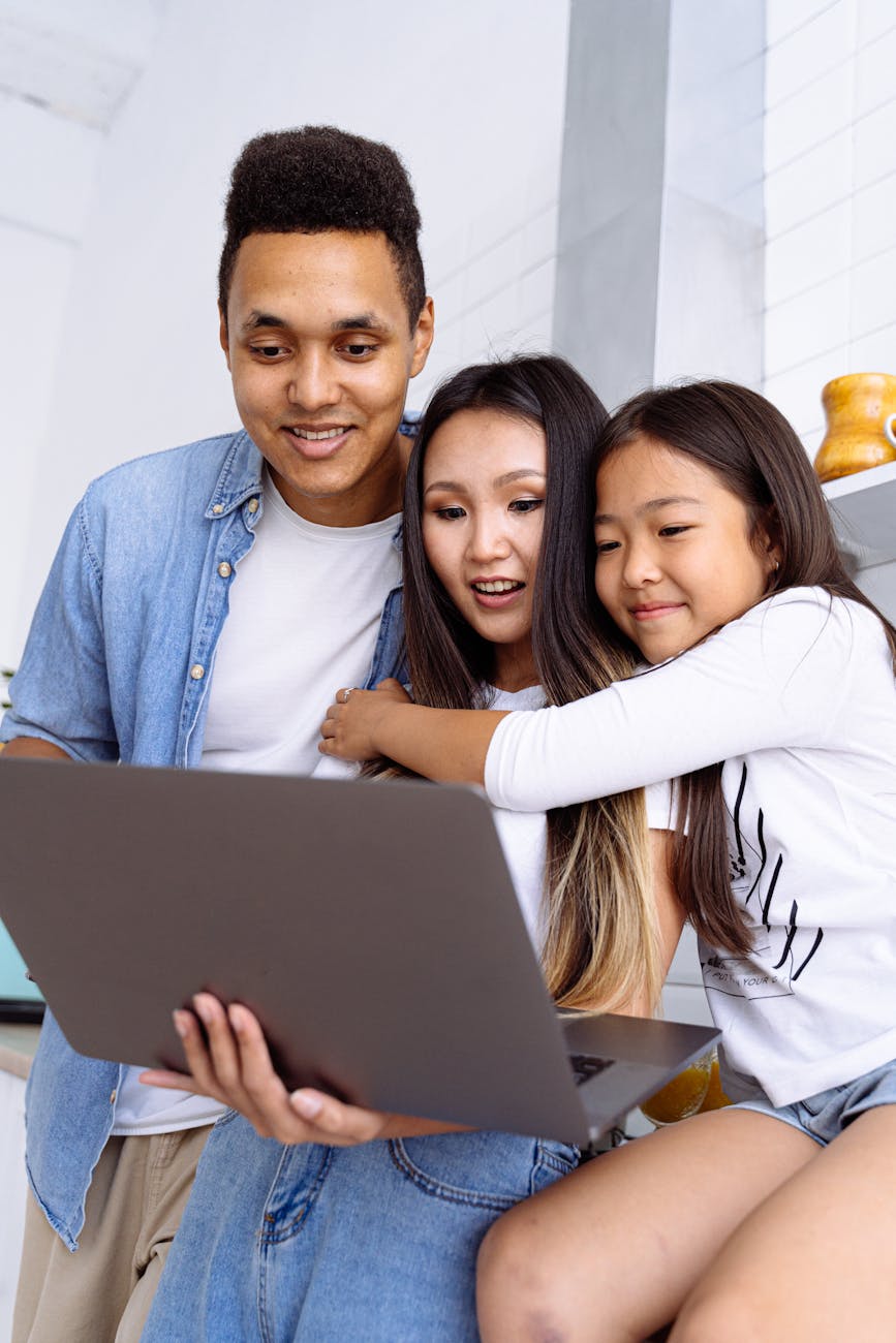 A family looking at a laptop together in a bright kitchen.